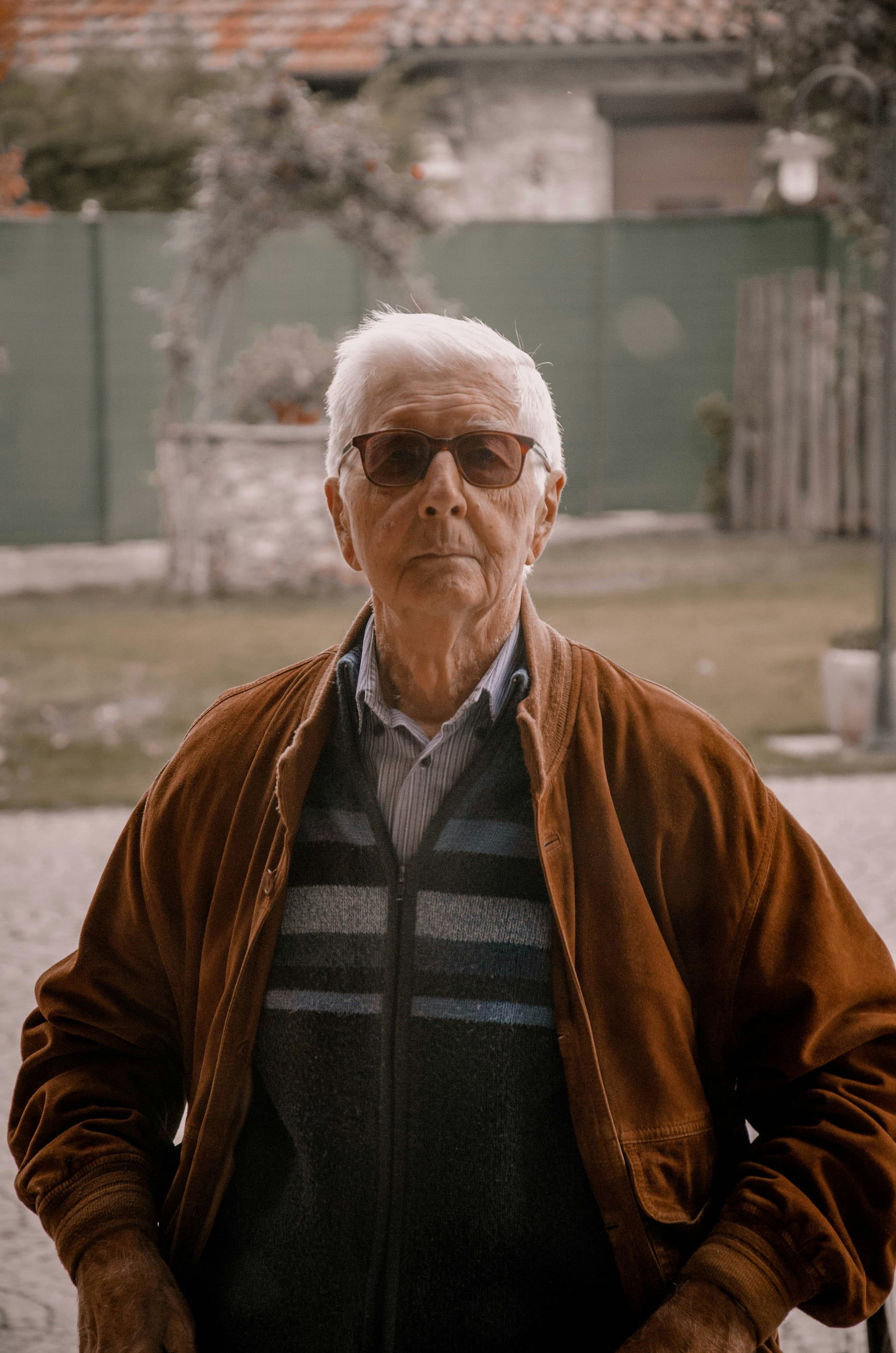 Elderly grandfather in brown jacket standing outdoors